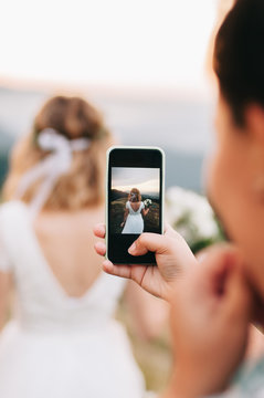 Girl captures beautiful wedding / bride  on the background of mountains by her smartphone. Wedding in mountains . Beauty of carpathian mountains, Ukraine