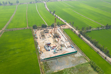 Oil and gas land drilling rig onshore in the middle of a rice field aerial view from a drone