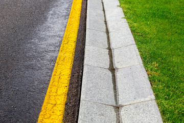 flowing rainwater in the canal is a cement ditch of a drainage system on the side of wet asphalt...