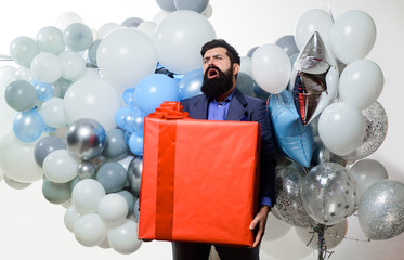 Birthday party. Happy birthday guy with helium balloons and big gift box. People, birthday, celebration. Festive event. Handsome man celebrating something. Bearded man in suit holds big birthday gift.
