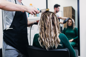 Beautiful hairstyle of mature woman after dying hair and making highlights in hair salon.