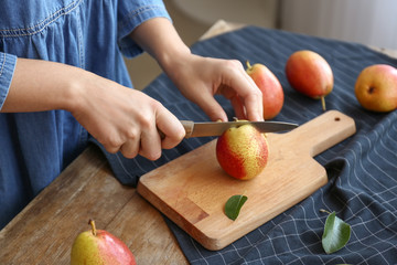 Woman cutting fresh pears at table, closeup