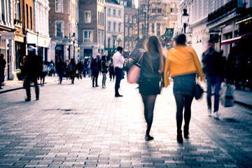Motion blurred people on busy street of shops