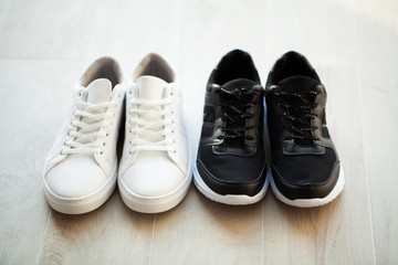 Pair of new stylish white and black sneakers on floor at home