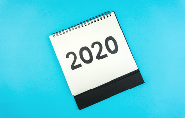New year 2020 concept: flat lay of desktop calendar isolated on blue