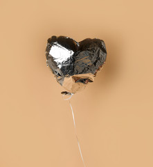 Party is over deflated silver heart balloon object  on beige background with shadow