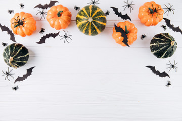 Halloween concept. Pumpkins, spiders and bats on white wooden background. Flat lay, top view, copy space