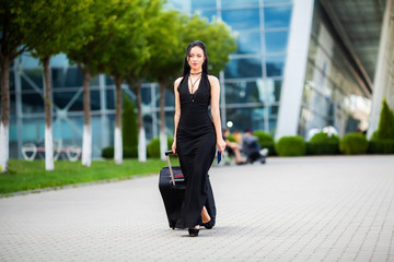 Fototapeta premium Young Cheerful Woman With a Suitcase. The Concept of Travel and work