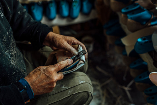 Hands of an old and experienced worker in the handmade shoe industry, carrying out assembly tasks with a clamp, in his work section, pulling the leather and then sticking it on the last.
