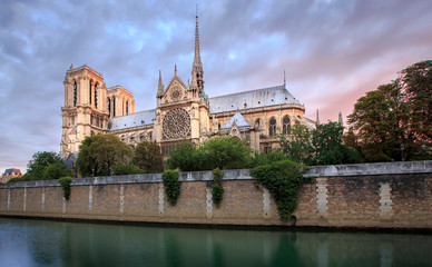 Naklejka premium Notre Dame Cathedral in Paris France just before sunrise. Photo shows the banks of the Seine river in the foreground.