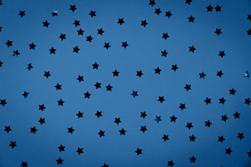 Star sprinkles on solid festive holiday background in trendy seasonal color. Color and celebration concept. Top view, flat lay. Horizontal