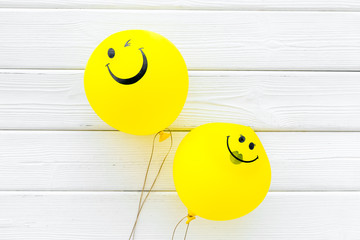 Happiness emotion. Yellow balloon with smile on white wooden background top view copy space