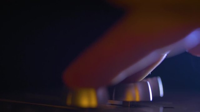 The hand of an audio engineer is moving a controller on the mixing cosole. This is a professional studio equipment.