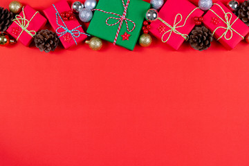 Christmas background concept. Top view of Christmas gift box with pine cones, red berries and bell on red background.