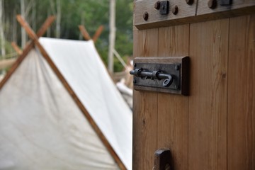 Historic wooden church door opens to ancient viking village made of white tents