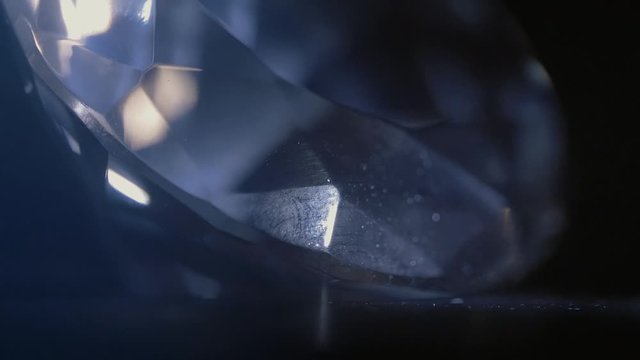 A huge cut diamond is shining and sparkling in the dark. Extra close up.