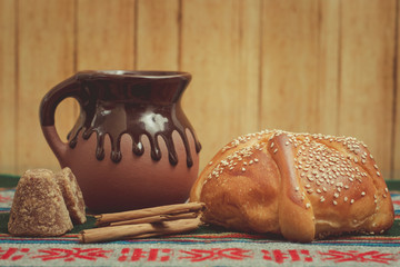 Pan de muerto y taza de chocolate sobre una mesa con mantel típico mexicano. Con ingredientes de...