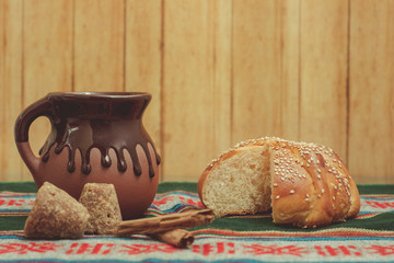 Pan de muerto y taza de chocolate sobre una mesa con mantel típico mexicano. Con ingredientes de...