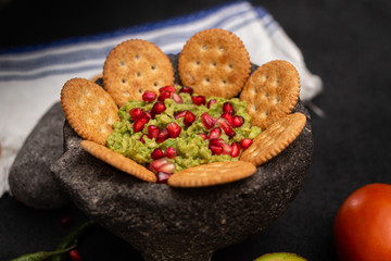 Avocadp paste served with crackers and topped with pomegranate fruit