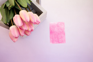 Bouquet of pink tulips in a wooden decorative box and greeting card. Selective focus