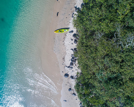 Man Kayaking In A Blue Ocean Near A Tropical Beach Perfect For Fitness, Fun, Fishing And Holidays. Aerial Shot At Sunrise.