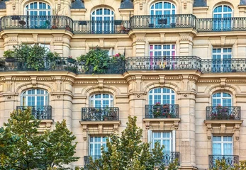 Schilderijen op glas Street view of an old, elegant residential building facade in Paris, with ornate details in the stone walls, french doors and wrought iron railings on the balconies. © Cheryl Ramalho
