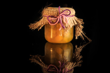 small glass jar of delicious yellow fruit jam with reflection