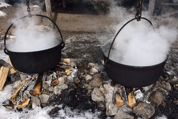Traditional method of evaporating sap in two cast iron pots to produce maple syrup - obrazy, fototapety, plakaty