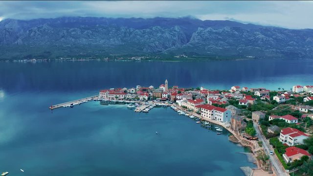 Aerial view of small coastal town in Croatia, idyllic harbor with boats, Velebit mountains in the background, picturesque seascape scene