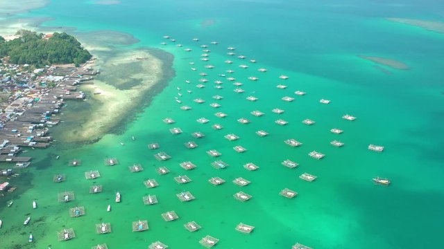 Aerial Drone Video flying above Fishing Village of Tanjung Binga in Belitung Island Indonesia. Fishing Boat on Clear water, village houses