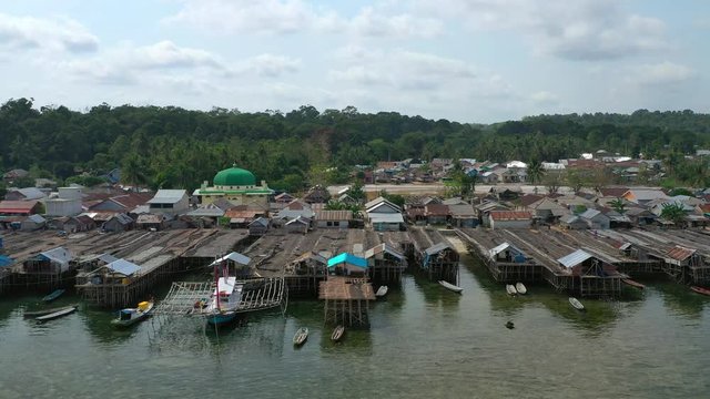 Aerial Drone Video flying above Fishing Village of Tanjung Binga in Belitung Island Indonesia. Fishing Boat on Clear water, village houses