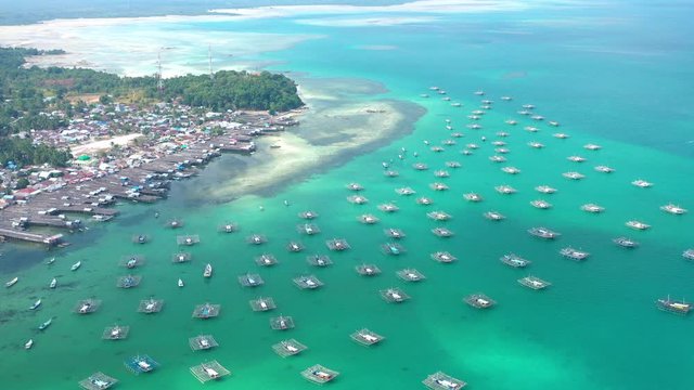 Aerial Drone Video flying above Fishing Village of Tanjung Binga in Belitung Island Indonesia. Fishing Boat on Clear water, village houses