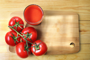 red tomato juice.  fresh tomato juice in a glass glass and ripe fruit on a light wooden Board. top view . copy space .