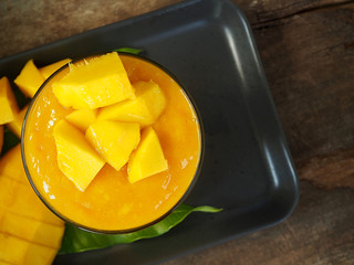 Top view Mango smoothie in glass with slices of mango fruit on wooden background. Taste sweet, tasty, drink for healthy