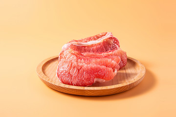 A plate of fresh red grapefruit meat on a yellow background