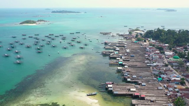 Aerial Drone Video flying above Fishing Village of Tanjung Binga in Belitung Island Indonesia. Fishing Boat on Clear water, village houses