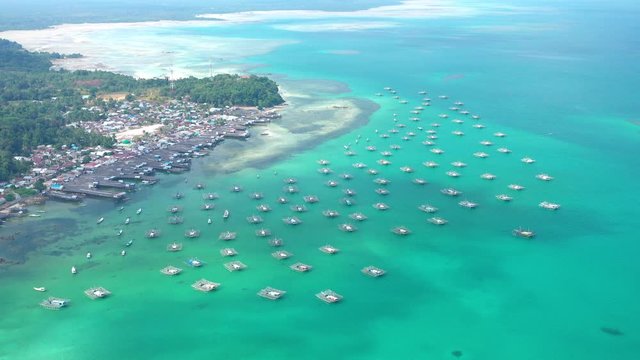 Aerial Drone Video flying above Fishing Village of Tanjung Binga in Belitung Island Indonesia. Fishing Boat on Clear water, village houses