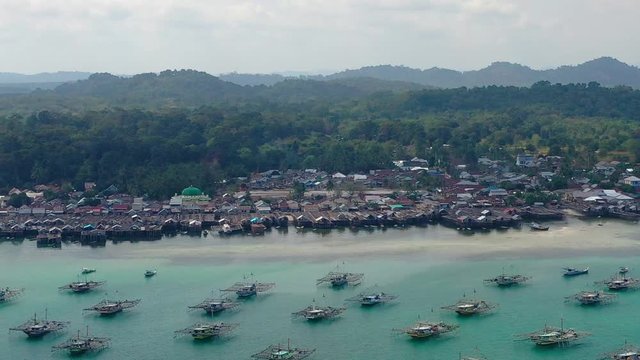 Aerial Drone Video flying above Fishing Village of Tanjung Binga in Belitung Island Indonesia. Fishing Boat on Clear water, village houses
