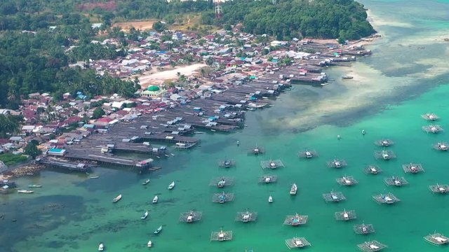 Aerial Drone Video flying above Fishing Village of Tanjung Binga in Belitung Island Indonesia. Fishing Boat on Clear water, village houses