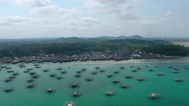 Aerial Drone Video flying above Fishing Village of Tanjung Binga in Belitung Island Indonesia. Fishing Boat on Clear water, village houses