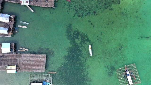 Aerial Drone Video flying above Fishing Village of Tanjung Binga in Belitung Island Indonesia. Fishing Boat on Clear water, village houses
