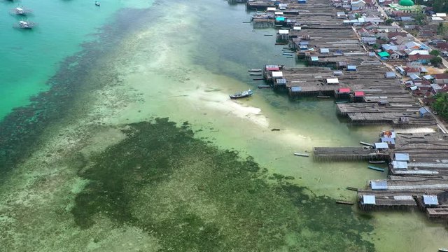 Aerial Drone Video flying above Fishing Village of Tanjung Binga in Belitung Island Indonesia. Fishing Boat on Clear water, village houses