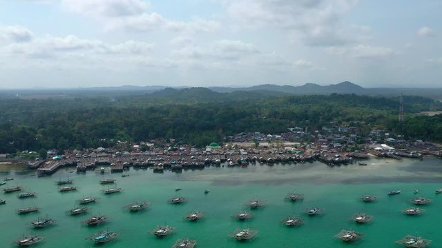 Aerial Drone Video flying above Fishing Village of Tanjung Binga in Belitung Island Indonesia. Fishing Boat on Clear water, village houses