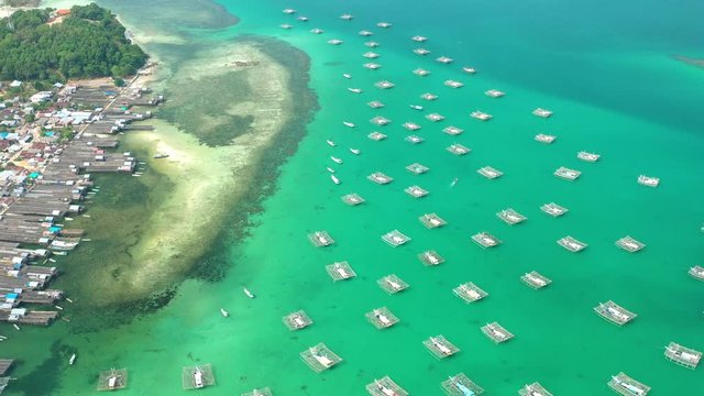Aerial Drone Video flying above Fishing Village of Tanjung Binga in Belitung Island Indonesia. Fishing Boat on Clear water, village houses