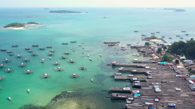 Aerial Drone Video flying above Fishing Village of Tanjung Binga in Belitung Island Indonesia. Fishing Boat on Clear water, village houses