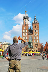 Obraz premium KRAKOW, POLAND - JULY 09, 2019: Tourist looks at the Mariacki church, Church of Our Lady Assumed into Heaven