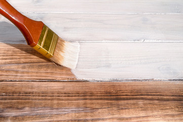 painting brush covers the wood textured floor with white paint