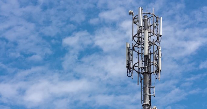 Cell tower on blue sky background. Floating clouds in blue sky, time lapse. 