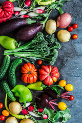 Fresh seasonal vegetables food background. Aubergines, tomatoes, radishes, peppers, broccoli, potatoes, beets on a dark background, top view. Flat lay