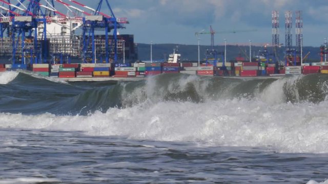 Container Terminal Cranes on Baltic Sea with Heavy Waves Splashing into Shore